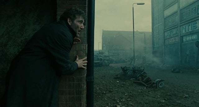 a man leaning against a brick wall in the middle of a street