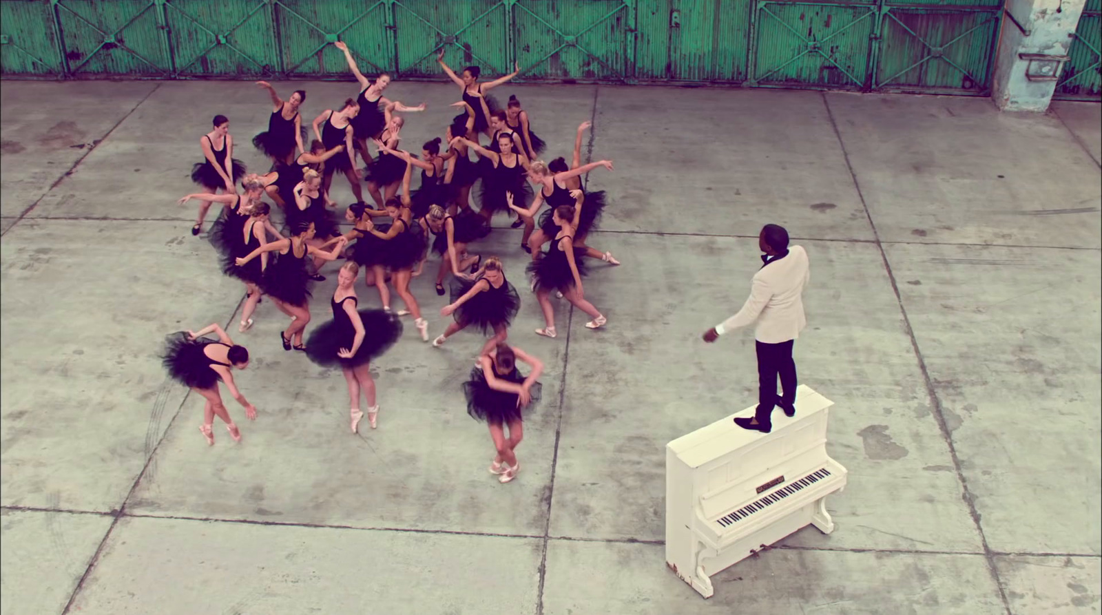 a man standing on top of a piano next to a group of dancers