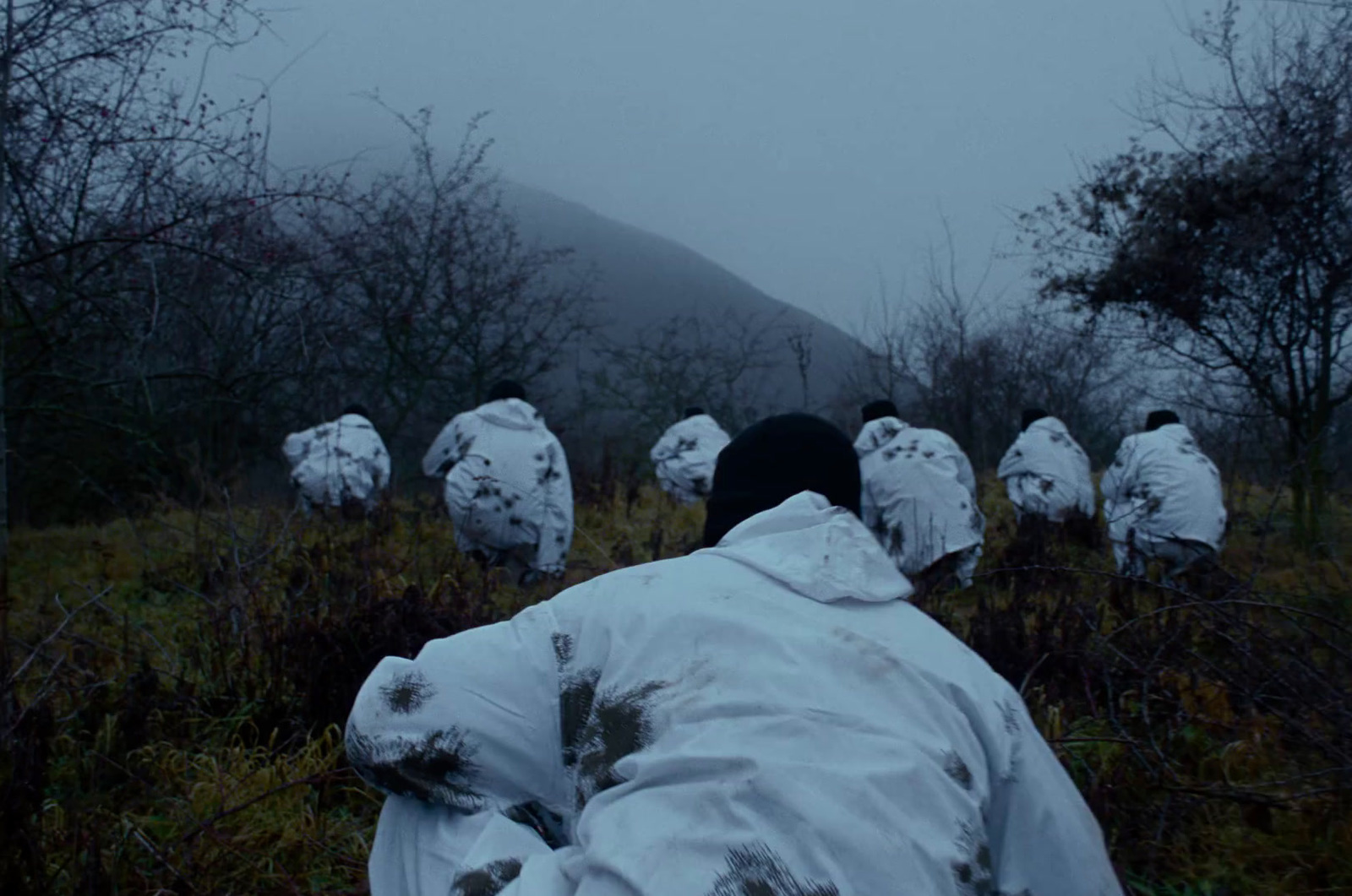 a man in a white coat is sitting in a field