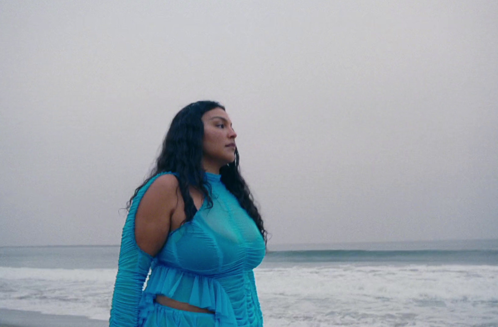 a woman standing on a beach next to the ocean