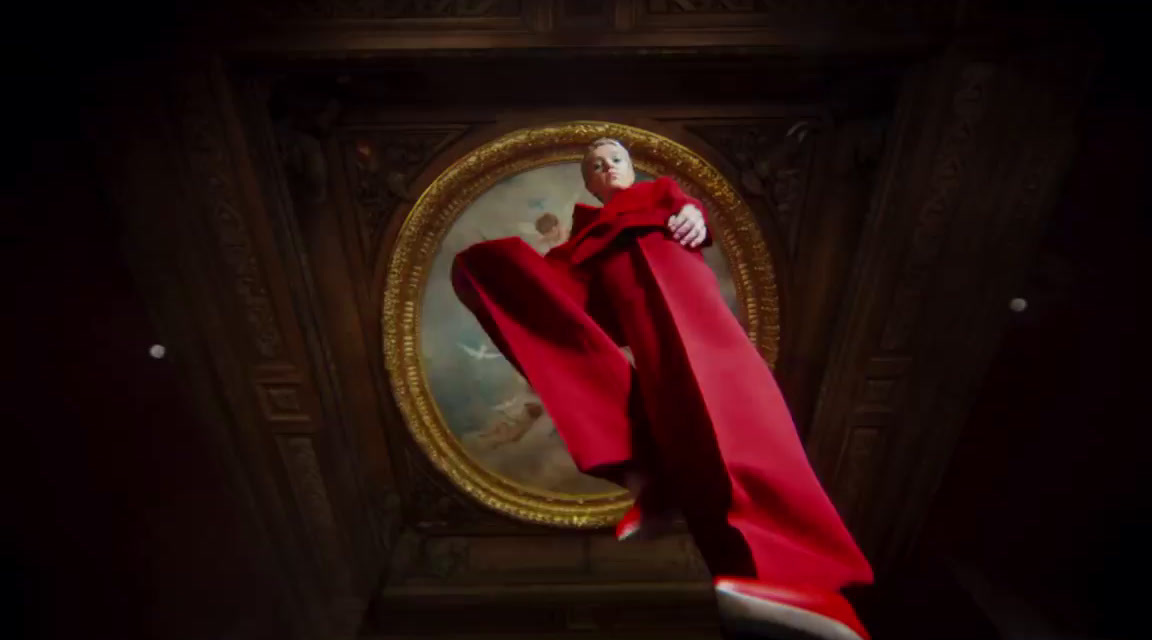 a man in a red robe standing in front of a painting