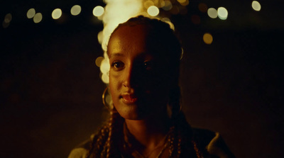 a woman standing in a dark room with lights in the background