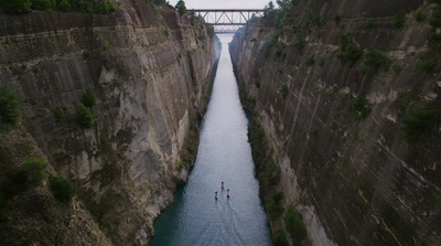 two people are rowing in a boat down a narrow river