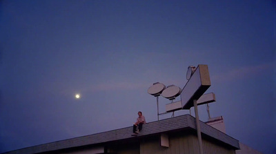 a man sitting on top of a building next to a satellite dish