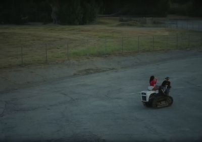 two people riding a motorcycle in a parking lot