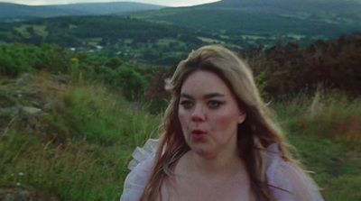 a woman with long hair standing in a field