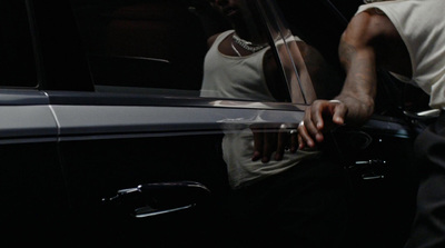 a man in a white tank top getting out of a car