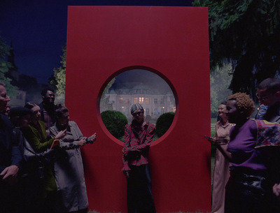 a group of people standing around a red sculpture