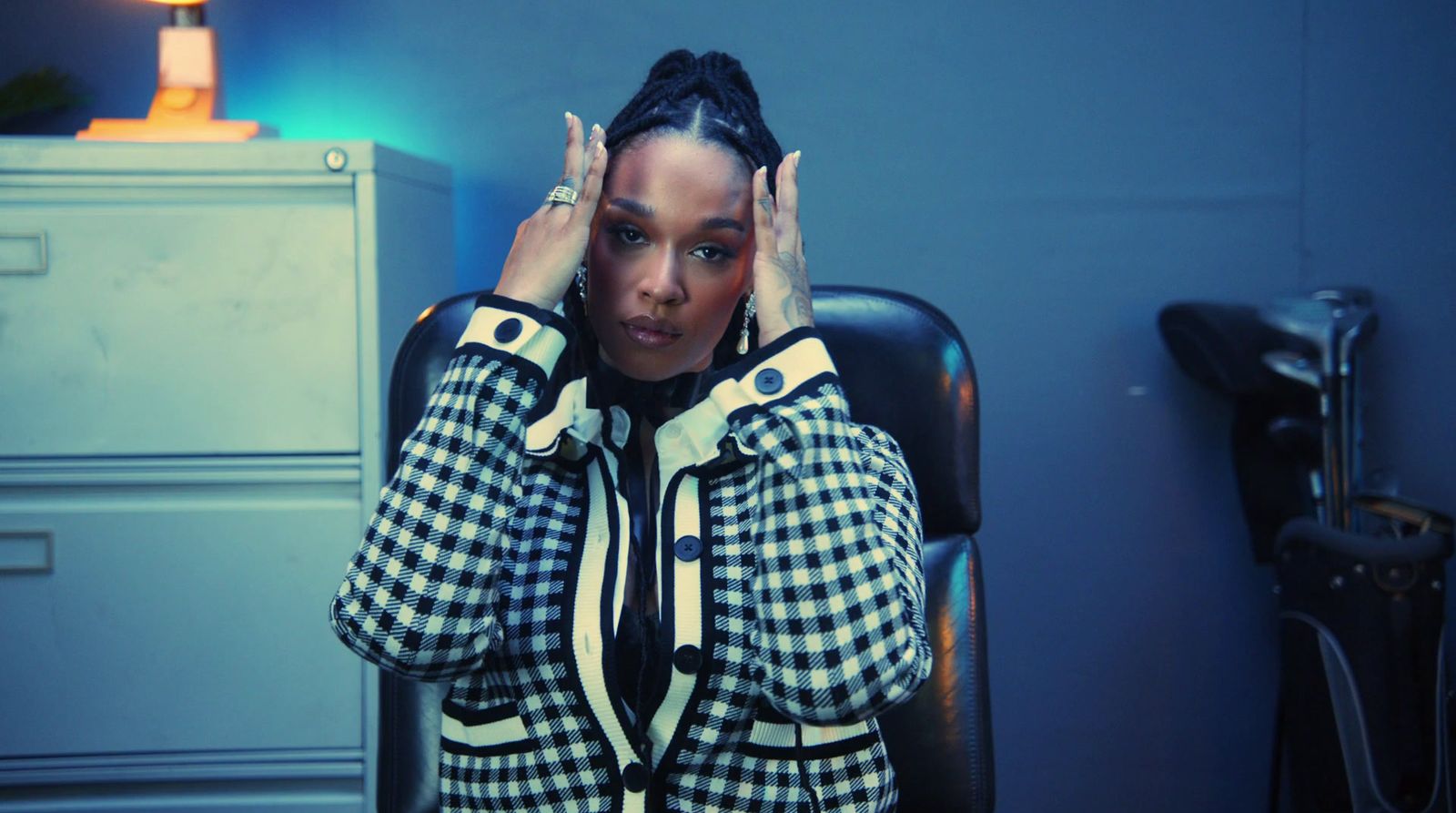 a woman sitting in a chair with her hands on her head