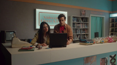 a man and a woman sitting at a desk with a laptop