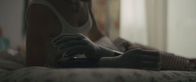 a woman sitting on a bed holding a remote control