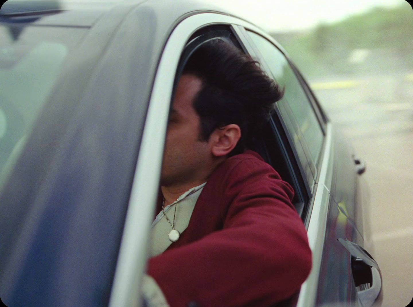 a man sitting in a car with his head out the window