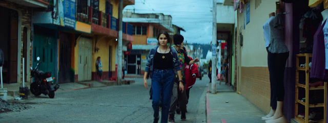 a group of people walking down a street next to tall buildings