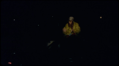 a woman in a yellow jacket sitting in the dark