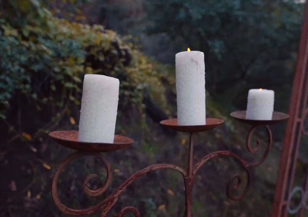 three white candles sitting on top of a metal stand