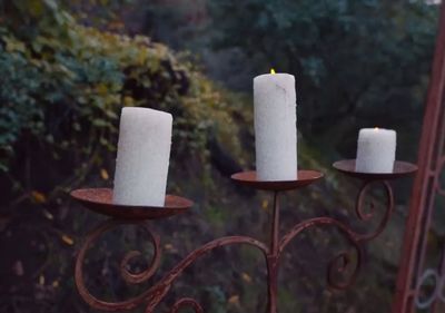 three white candles sitting on top of a metal stand