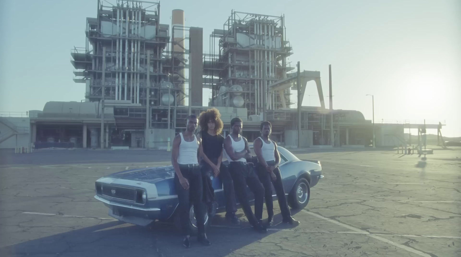 a group of people standing next to a car in a parking lot