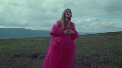 a woman in a pink dress standing in a field