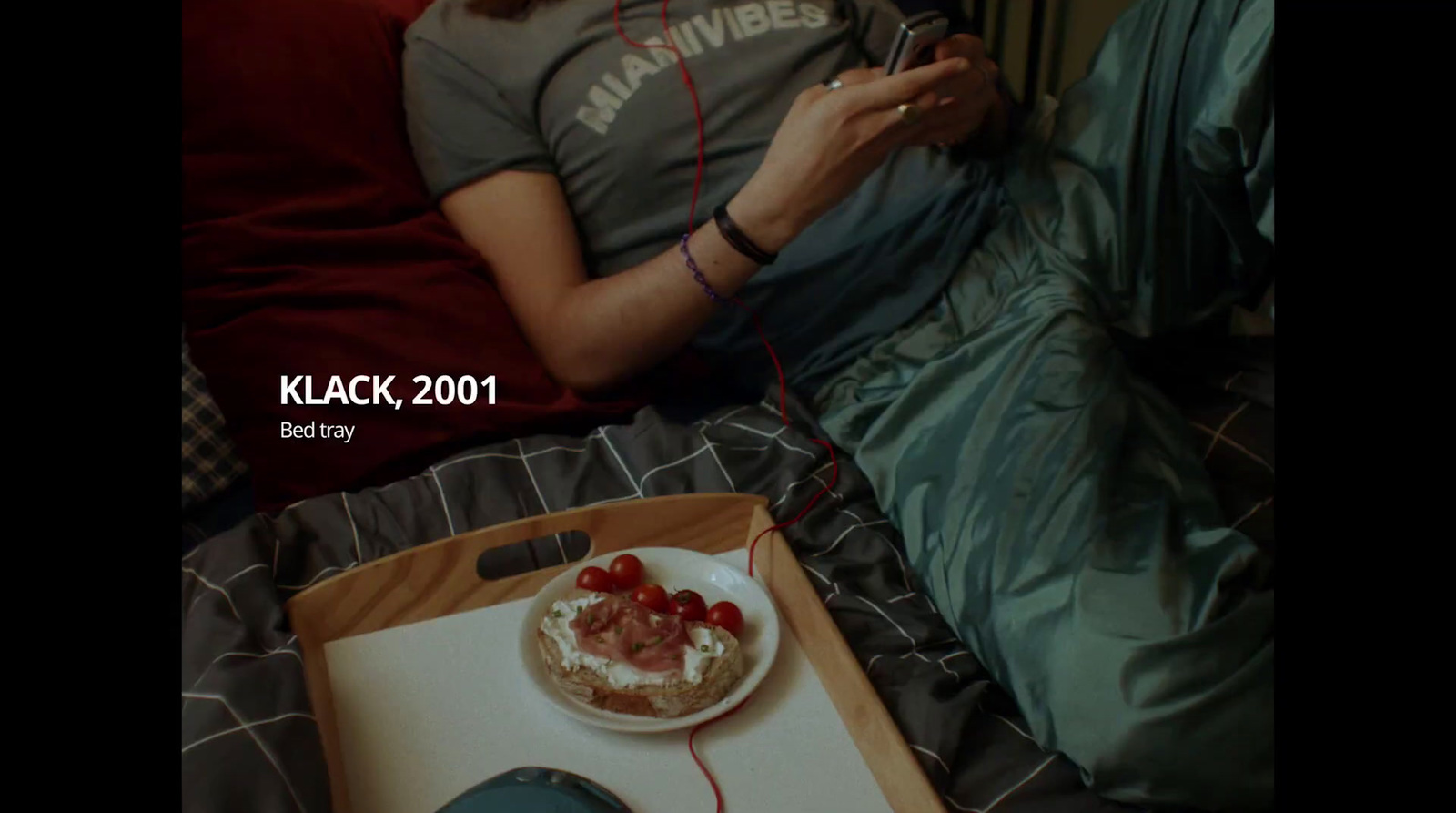 a person sitting on a bed with a plate of food