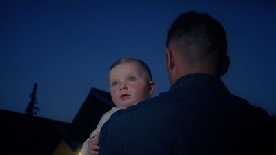 a man holding a baby in his arms at night