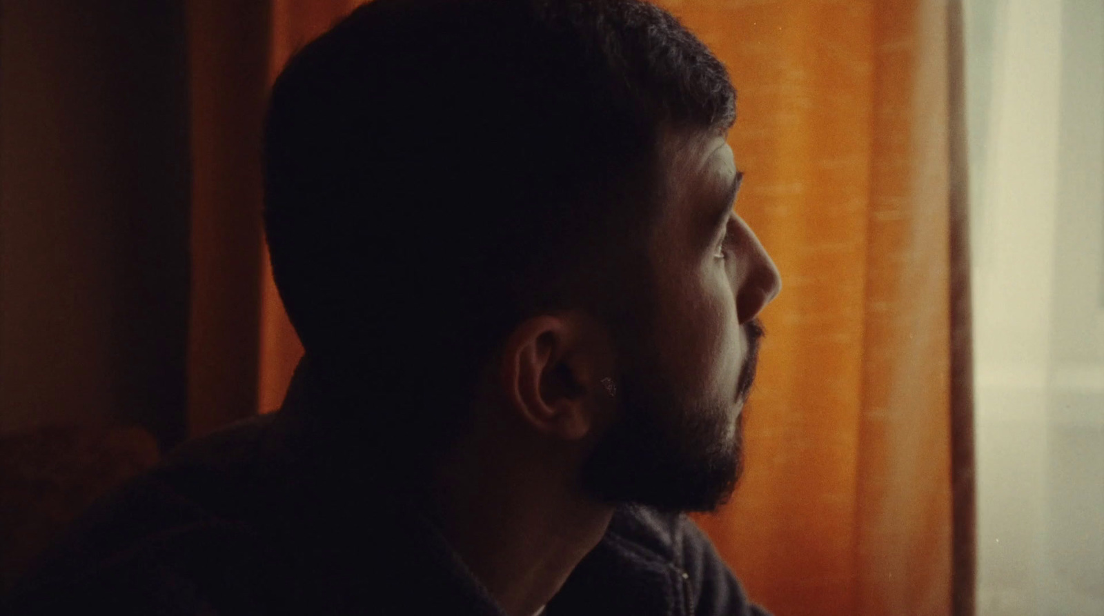 a man looking out of a window in a dark room