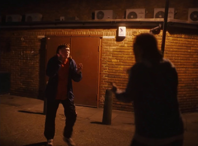 a man standing in front of a brick building talking on a cell phone