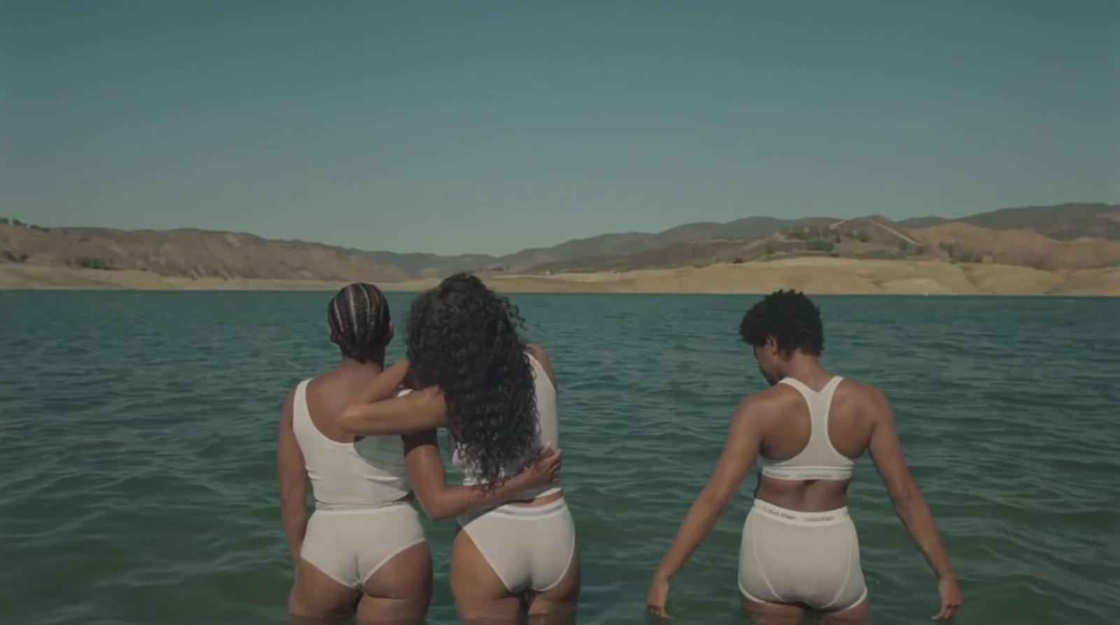 three women in white swimsuits standing in the water