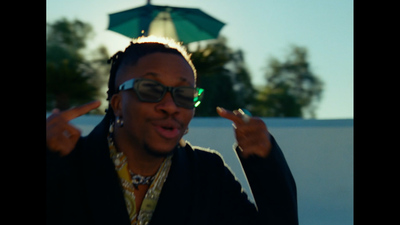 a man with sunglasses and a necklace making a peace sign