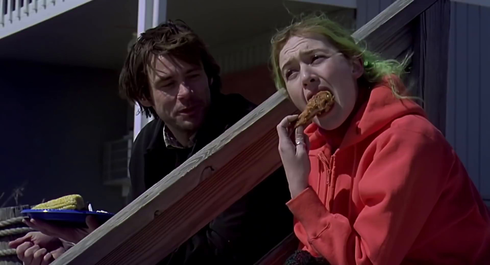 a woman eating a donut while standing next to a man