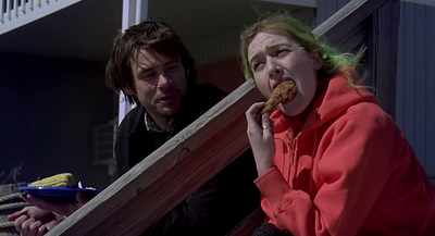 a woman eating a donut while standing next to a man