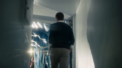 a man walking down a hallway next to a white wall