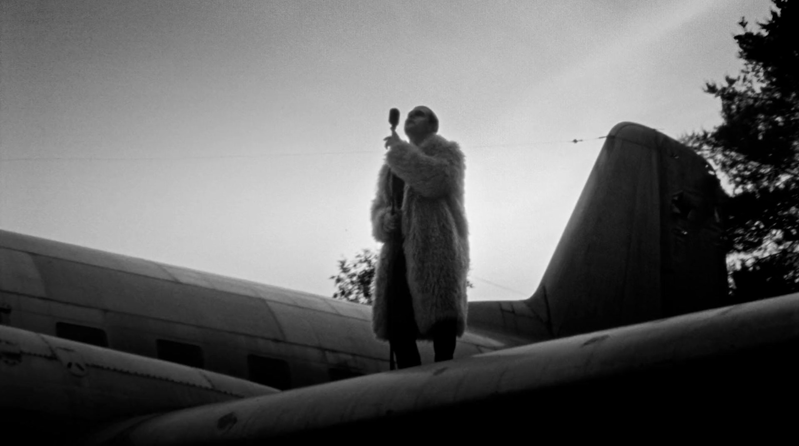 a man in a fur coat standing on top of an airplane