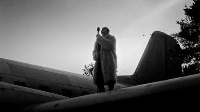 a man in a fur coat standing on top of an airplane