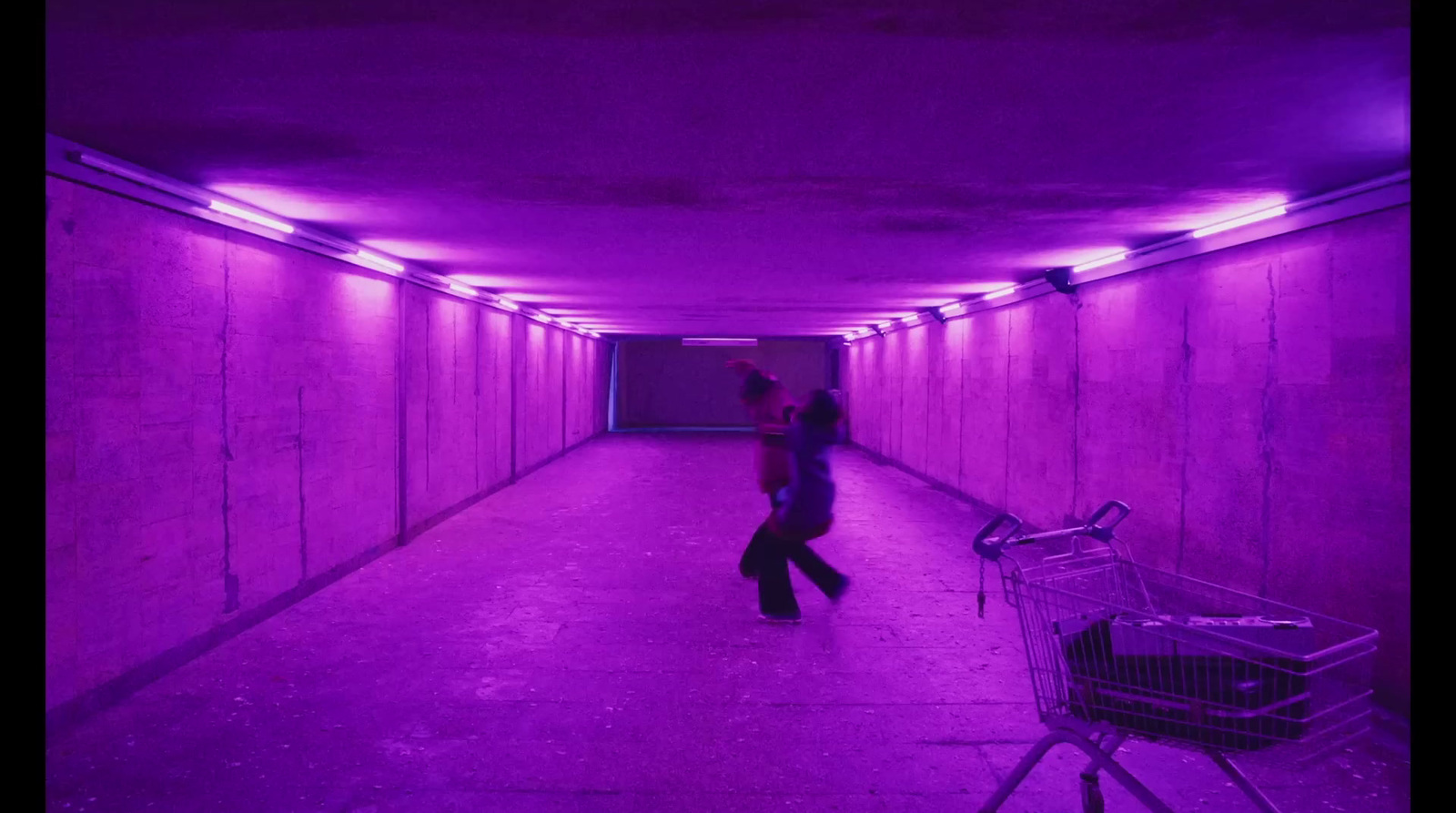 a woman walking through a tunnel with a shopping cart