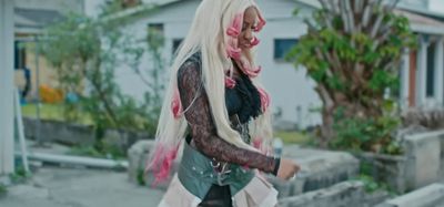 a woman with long white hair and pink hair walking down a street