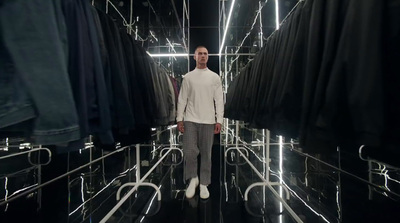 a man standing in a room with a lot of clothes