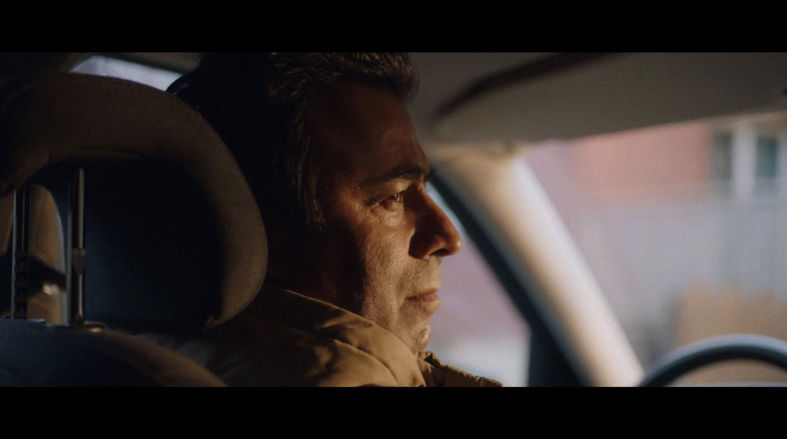 a man sitting in a car looking out the window