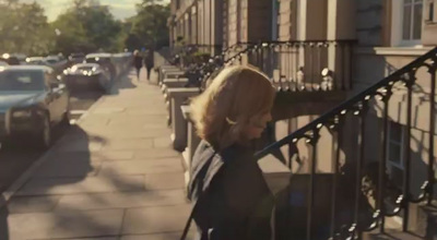 a woman walking down a street next to parked cars