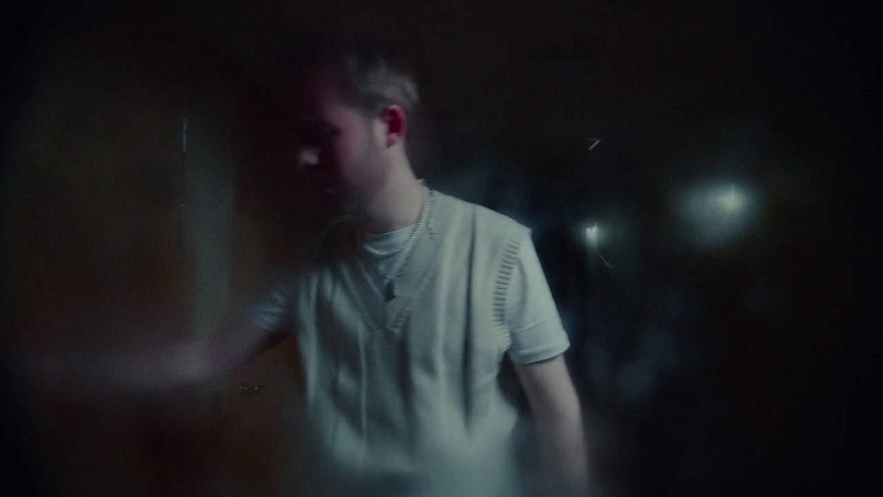 a man in a white shirt standing in a dark room