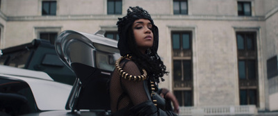 a woman in a black dress standing in front of a car