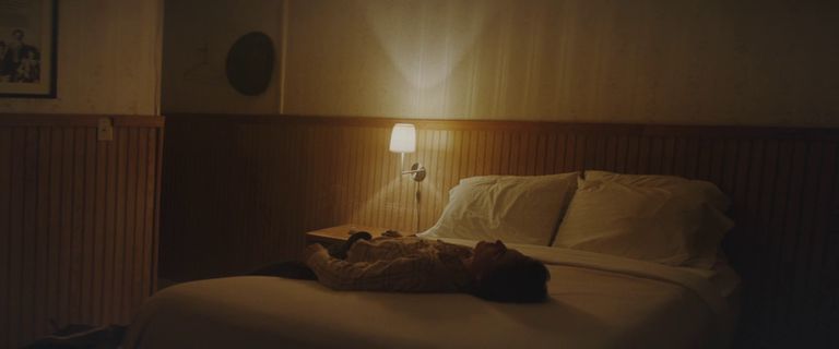 a cat laying on a bed in a dimly lit room