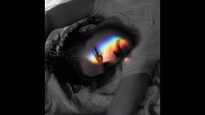 a woman laying on a bed with a rainbow painted on her face