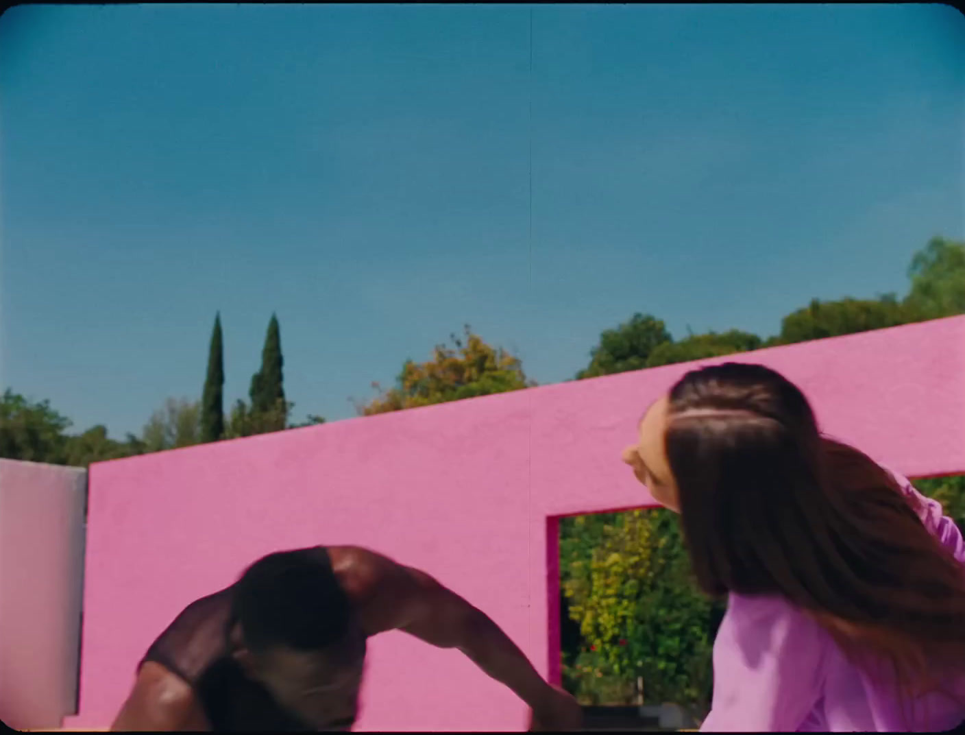 a man and a woman standing in front of a pink wall