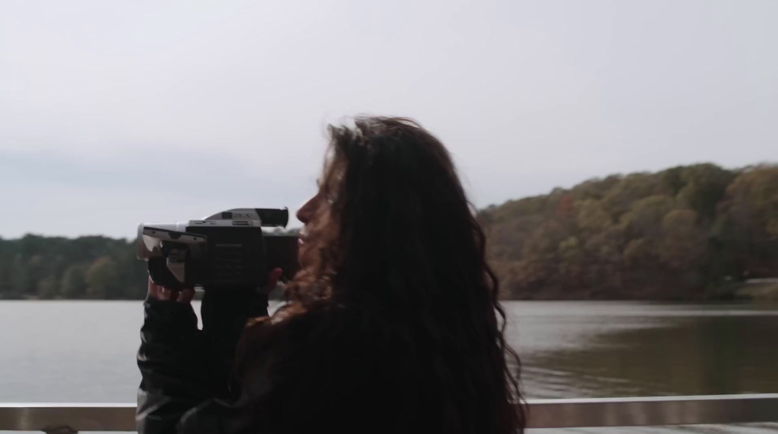 a woman taking a picture of a body of water