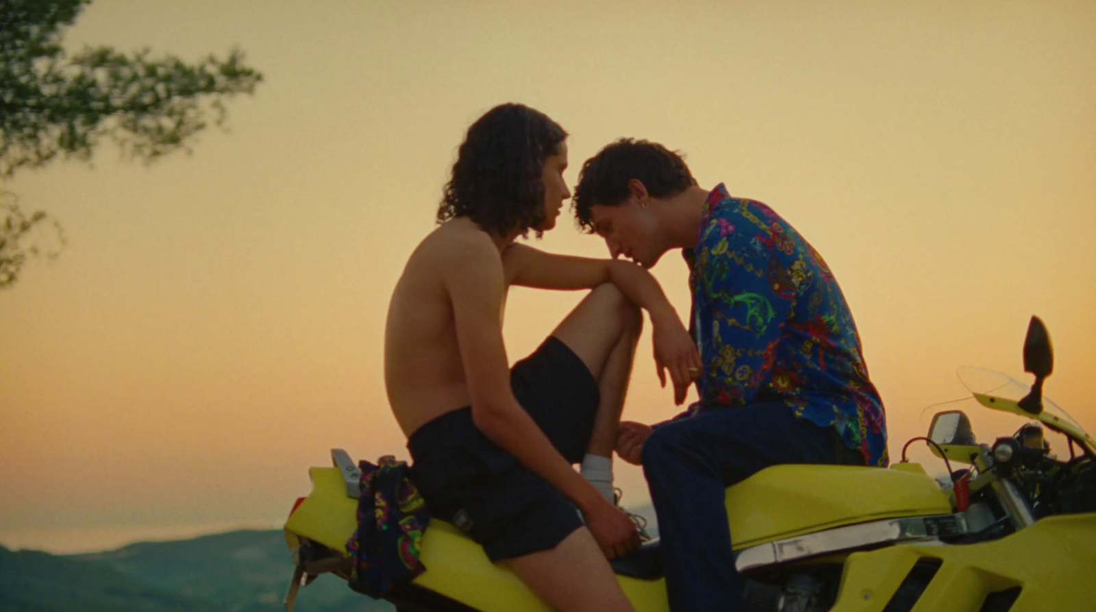 a man and a woman sitting on a yellow motorcycle