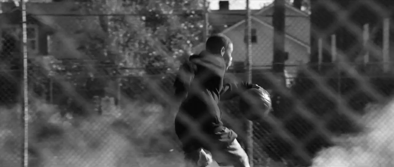 a man holding a baseball in front of a fence