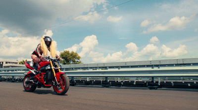 a woman riding a red motorcycle down a street