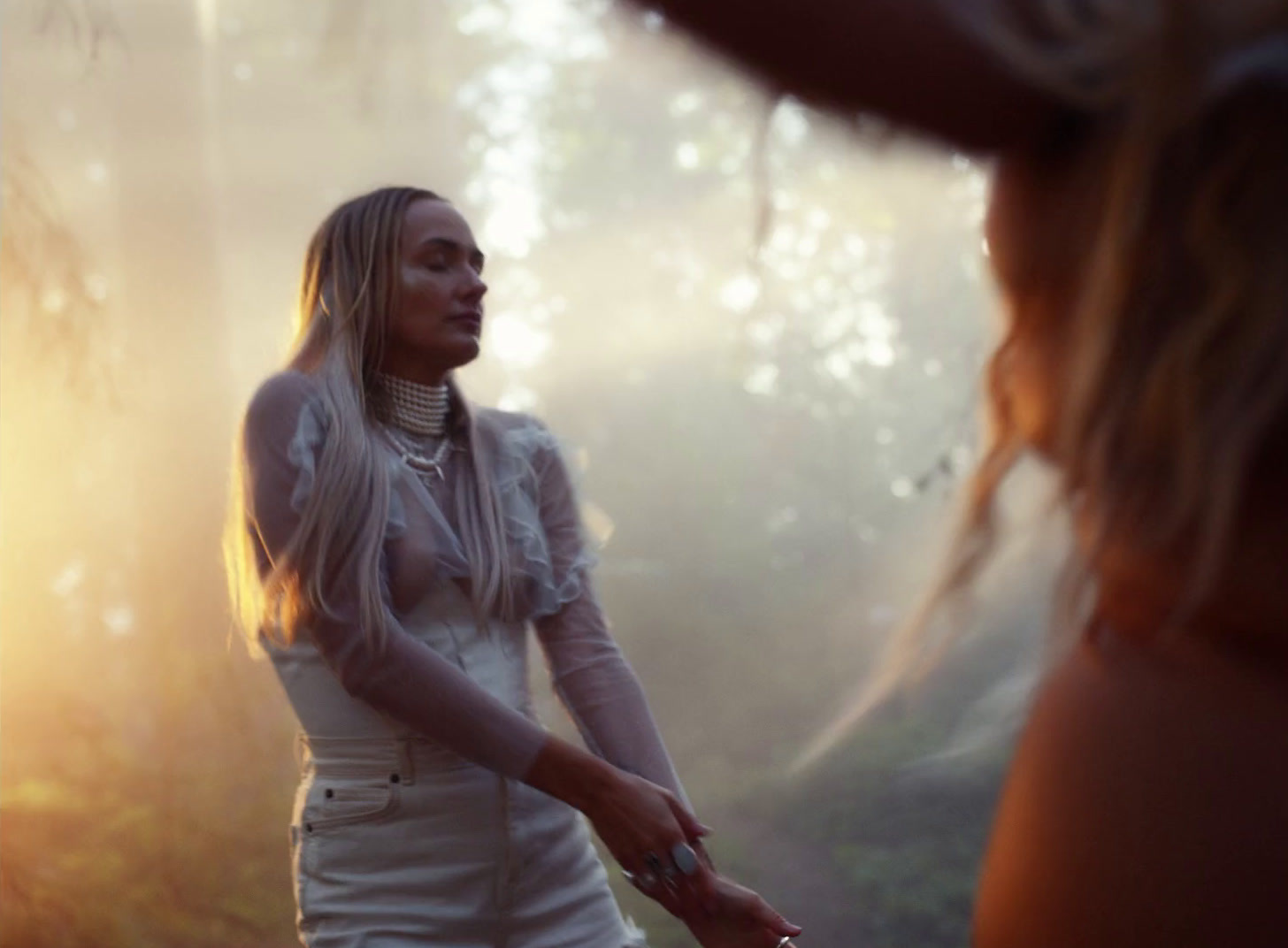 a woman in a white dress standing in a forest