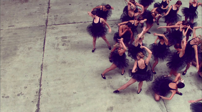 a group of women in black dresses dancing on a sidewalk