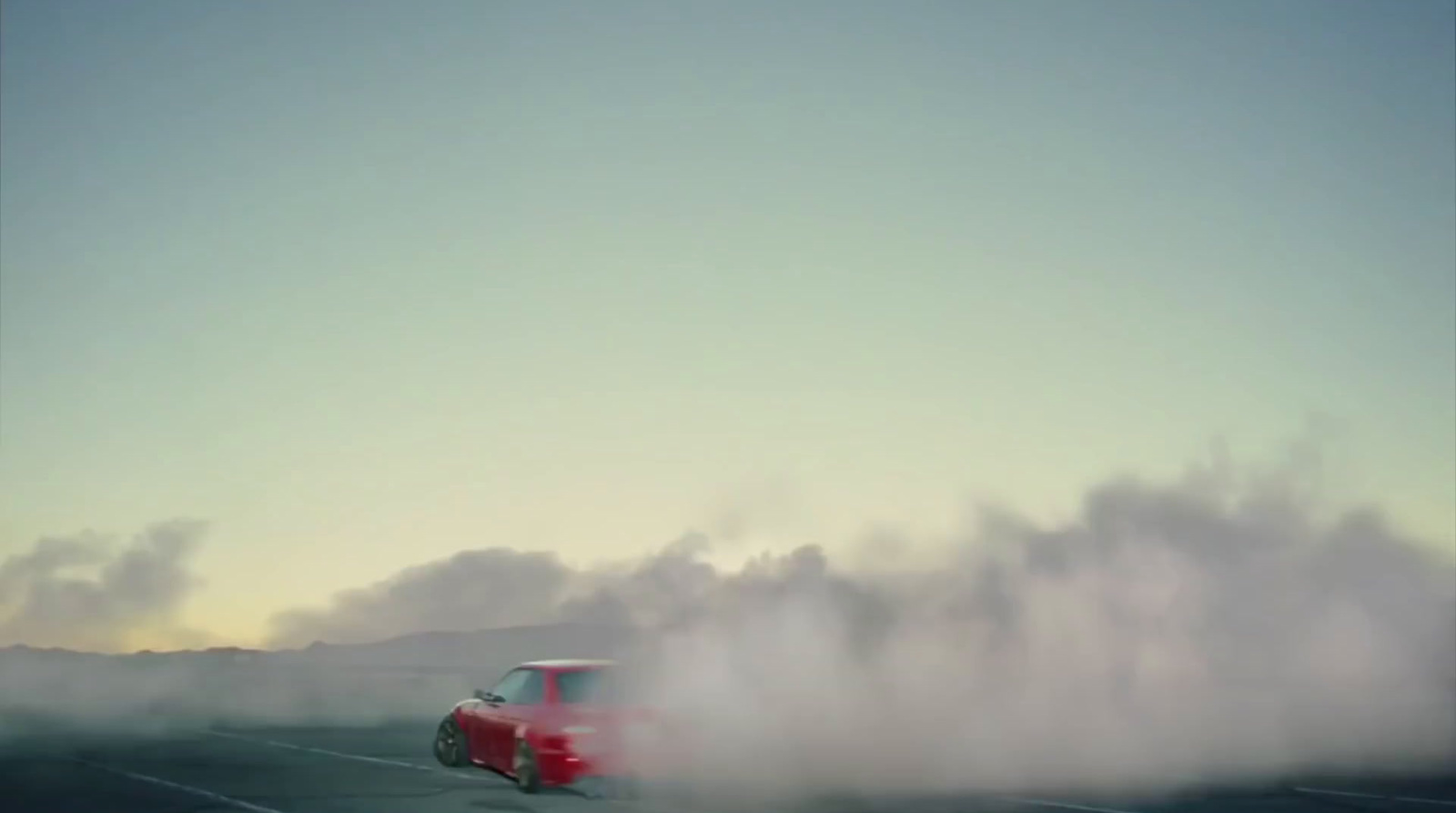 a red car driving down a road with a lot of smoke coming out of it